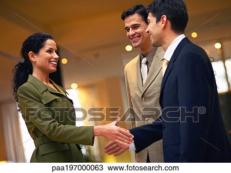 Stock Image - Businesspeople, woman and man about to shake hands. Fotosearch