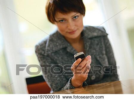 Businesswoman holding cell phone, looking at camera. View Large Photo Image Stock Photo - Businesswoman holding cell phone, looking at camera.. Fotosearch