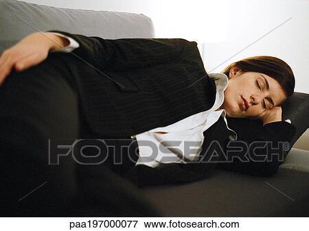 Stock Photo - Businesswoman lying on couch, eyes closed.. Fotosearch