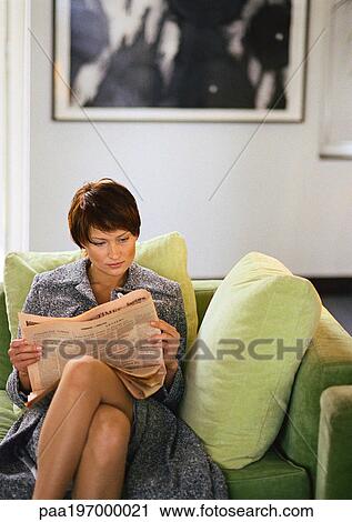 Stock Image - Businesswoman sitting reading newspaper. Fotosearch