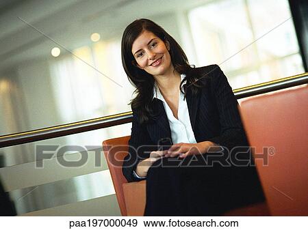 Stock Photo - Businesswoman sitting, smiling at camera, portrait, tilt. Fotosearch