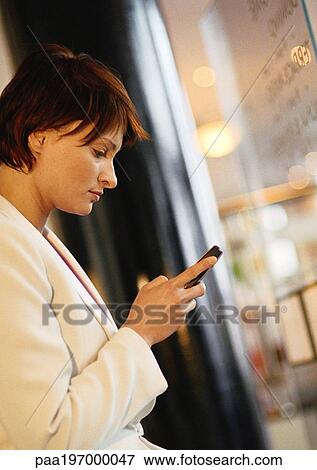 Stock Photo - Businesswoman using cell phone, side view.. Fotosearch