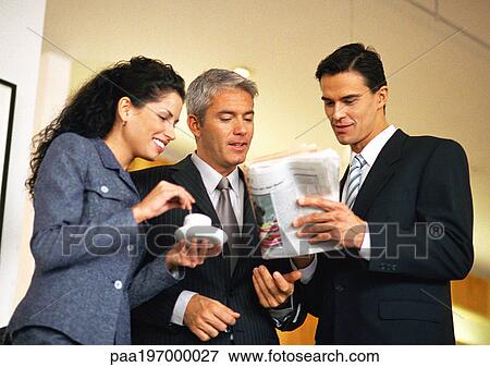 Group of business people looking at newspaper together, waist up, low angle view View Large Photo Image Stock Photo - Group of business people looking at newspaper together, waist up, low angle view. Fotosearch