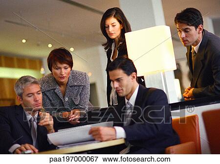 Group of business people, standing and sitting, looking at document, tilt View Large Photo Image Stock Photo - Group of business people, standing and sitting, looking at document, tilt. Fotosearch