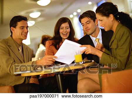 Stock Image - Group of people sitting together, looking at document. Fotosearch