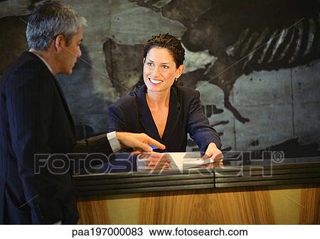 Man standing in front of woman at counter, man pointing to paper in woman's hands View Large Photo Image Stock Image - Man standing in front of woman at counter, man pointing to paper in woman's hands. Fotosearch