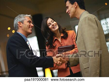 Men shaking hands, woman behind them. View Large Photo Image Stock Image - Men shaking hands, woman behind them.. Fotosearch