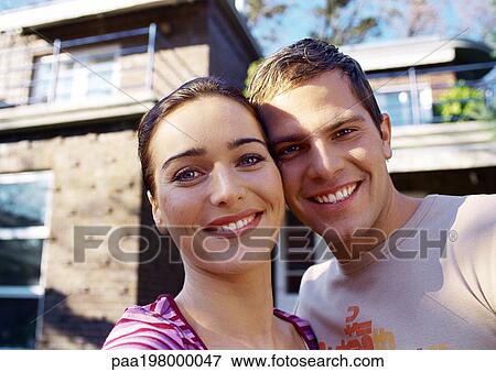 Man and woman standing cheek to cheek, smiling in front of a house View Large Photo Image Stock Photo - Man and woman standing cheek to cheek, smiling in front of a house. Fotosearch