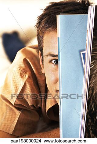 Man hiding his face behind magazines, close-up View Large Photo Image Picture - Man hiding his face behind magazines, close-up. Fotosearch