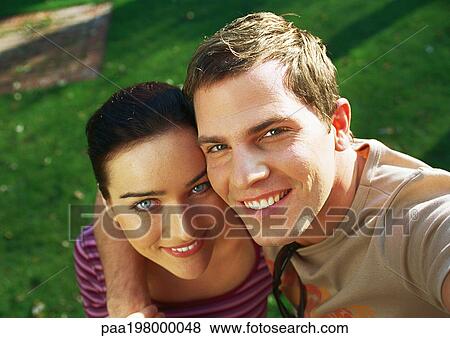 Stock Photo - Man's arm around woman's shoulder, looking up and smiling. Fotosearch
