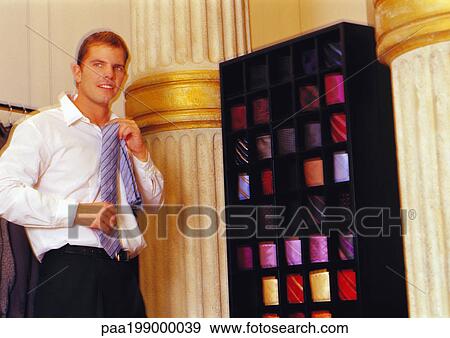 Man holding up tie to neck in store, blurred. View Large Photo Image Stock Photo - Man holding up tie to neck in store, blurred.. Fotosearch
