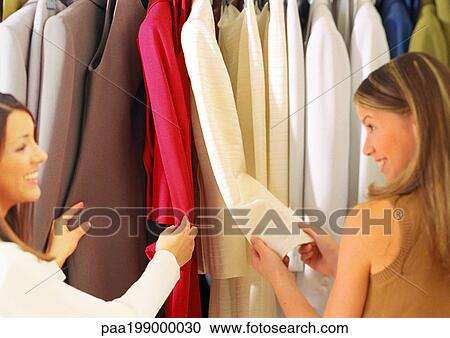 Two young women looking through women's suits in store. View Large Photo Image Stock Image - Two young women looking through women's suits in store.. Fotosearch