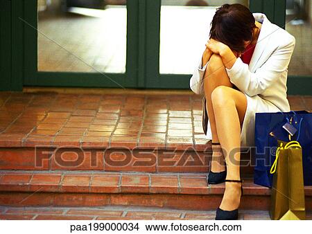 Woman in business clothes sitting on steps with head down, hands on knee, bags to the side. View Large Photo Image Picture - Woman in business clothes sitting on steps with head down, hands on knee, bags to the side.. Fotosearch