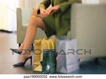 Woman in heels sitting, shopping bags on floor to the side, lower section View Large Photo Image Stock Image - Woman in heels sitting, shopping bags on floor to the side, lower section. Fotosearch