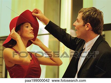 Woman trying on hat for man, man flipping front of hat. View Large Photo Image Stock Image - Woman trying on hat for man, man flipping front of hat.. Fotosearch