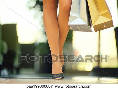 Woman walking in heels with shopping bags, low section View Large Photo Image Stock Photo - Woman walking in heels with shopping bags, low section. Fotosearch
