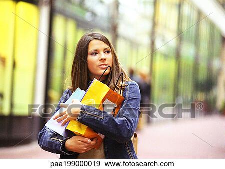 Young woman holding shopping bags in arms View Large Photo Image Stock Photo - Young woman holding shopping bags in arms. Fotosearch