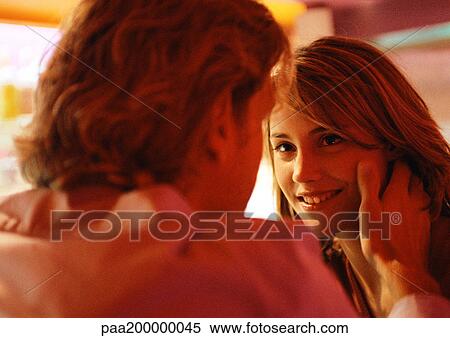 Stock Photography - Man and woman looking at each other, man touching her face.. Fotosearch