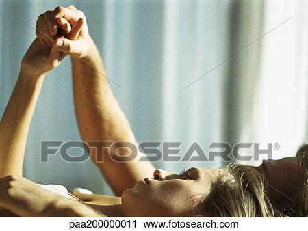 Man and woman lying in bed, man looking at woman's hand. View Large Photo Image Stock Image - Man and woman lying in bed, man looking at woman's hand.. Fotosearch