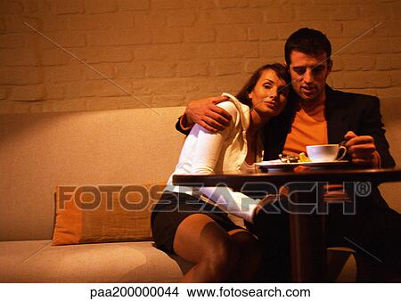 Man and woman sitting at table, woman leaning on man. View Large Photo Image Picture - Man and woman sitting at table, woman leaning on man.. Fotosearch