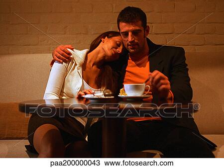 Man and woman sitting at table, woman leaning on man's shoulder View Large Photo Image Stock Image - Man and woman sitting at table, woman leaning on man's shoulder. Fotosearch