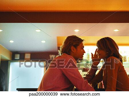 Stock Photo - Man and woman sitting, man touching woman's face.. Fotosearch