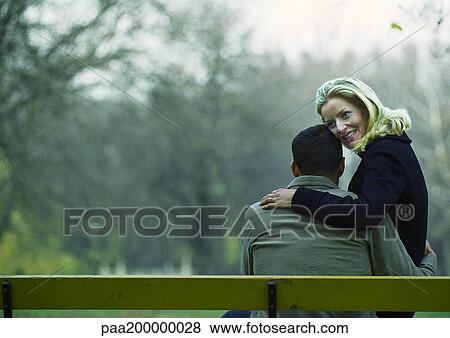 Man and woman sitting on bench, woman on his lap, view from behind. View Large Photo Image Stock Photo - Man and woman sitting on bench, woman on his lap, view from behind.. Fotosearch