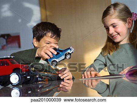 Boy and girl playing together at table with toy cars. View Large Photo Image Stock Photo - Boy and girl playing together at table with toy cars.. Fotosearch