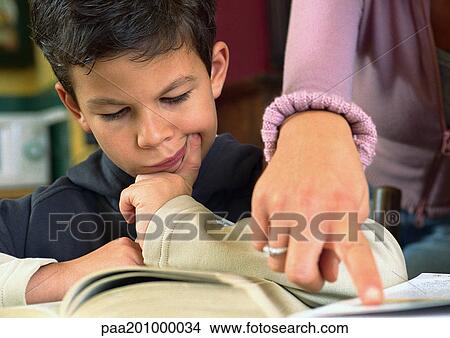 Child looking at book, woman's hand pointing at paper, close up. View Large Photo Image Picture - Child looking at book, woman's hand pointing at paper, close up.. Fotosearch