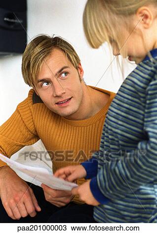 Stock Image - Daughter showing father paper.. Fotosearch