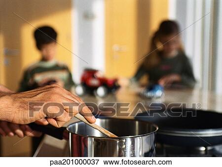 Father cooking in kitchen, children playing at table in background. View Large Photo Image Stock Photo - Father cooking in kitchen, children playing at table in background.. Fotosearch