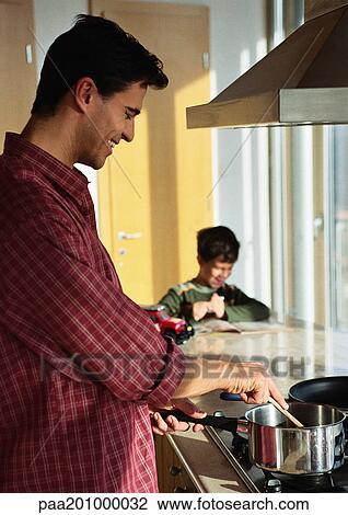 Father cooking, son in background looking at book. View Large Photo Image Stock Image - Father cooking, son in background looking at book.. Fotosearch