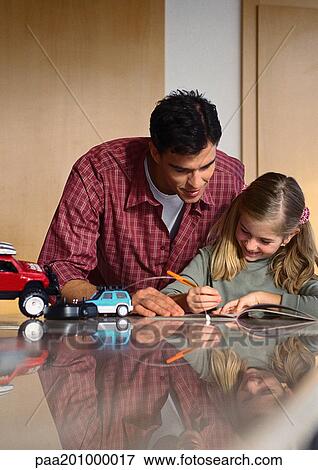 Stock Photo - Father looking at what daughter is writing.. Fotosearch