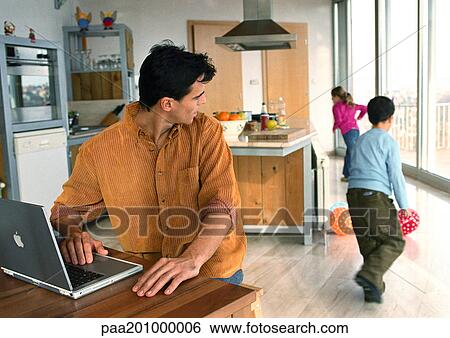 Stock Photograph - Father looking back at children playing with balls in the house.. Fotosearch
