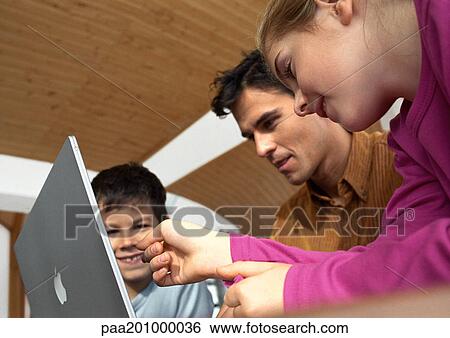 Father, son and daughter looking at laptop computer together. View Large Photo Image Stock Photograph - Father, son and daughter looking at laptop computer together.. Fotosearch