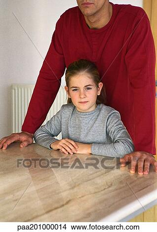 Picture - Father standing over daughter at table.. Fotosearch