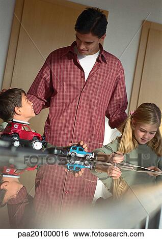 Father standing over son and daughter playing. View Large Photo Image Stock Photograph - Father standing over son and daughter playing.. Fotosearch