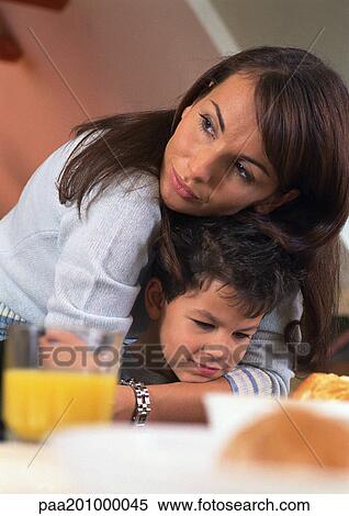 Mother hugging son sitting at table. View Large Photo Image Stock Photography - Mother hugging son sitting at table.. Fotosearch