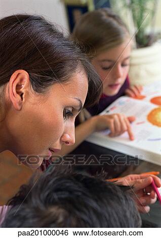 Mother working with child, daughter in background reading. View Large Photo Image Stock Photograph - Mother working with child, daughter in background reading.. Fotosearch
