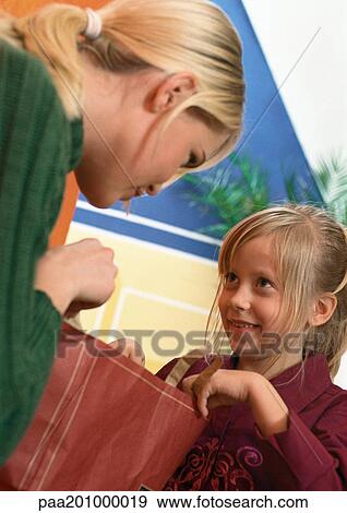 Woman holding shopping bag, little girl looking up at woman, holding other side of shopping bag, close-up View Large Photo Image Stock Photo - Woman holding shopping bag, little girl looking up at woman, holding other side of shopping bag, close-up. Fotosearch