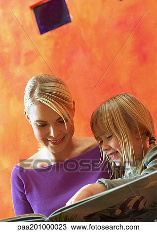 Young woman and little girl looking at book, head and shoulders View Large Photo Image Stock Image - Young woman and little girl looking at book, head and shoulders. Fotosearch