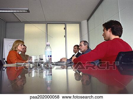 Stock Photo - Business people sitting at table in meeting room.. Fotosearch