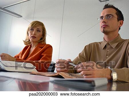 Businessman and businesswoman sitting at table next to each other. View Large Photo Image Stock Image - Businessman and businesswoman sitting at table next to each other.. Fotosearch