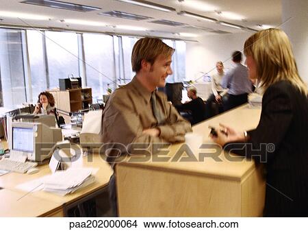 Picture - Businessman and businesswoman talking in office.. Fotosearch