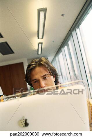 Stock Image - Businessman in office looking at computer. Fotosearch