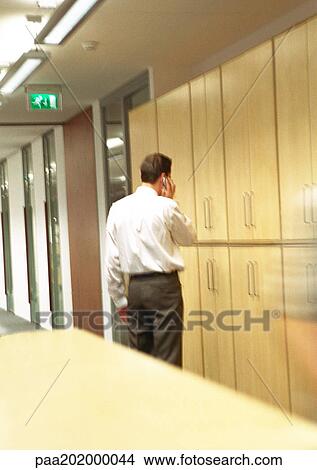 Businessman on phone standing in hallway. View Large Photo Image Picture - Businessman on phone standing in hallway.. Fotosearch