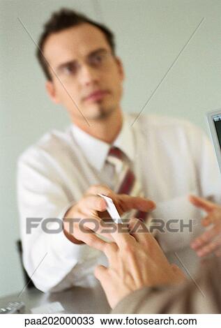 Stock Image - Businessmen exchanging a business card. Fotosearch