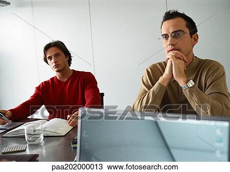 Stock Image - Businessmen sitting at table.. Fotosearch