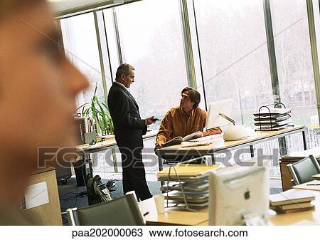 Stock Image - Businessmen talking in office.. Fotosearch