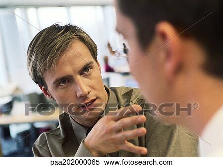 Stock Photography - Businessmen talking to each other in office.. Fotosearch